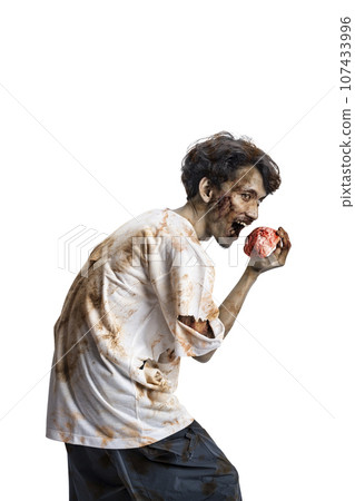 A scary zombie with blood and wounds on his body walking while eating a human brain 107433996