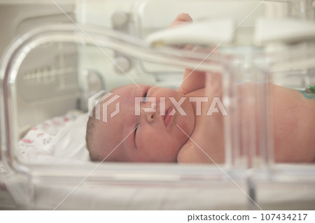 Newborn premature baby in NICU intensive care unit 107434217