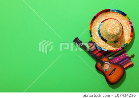 Mexican carpet, guitar and sombrero on green background. 107434286