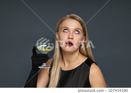 A girl at a party in the style of Halloween with a cocktail in her hands 107434390