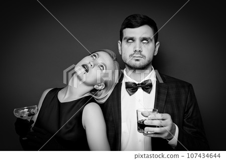 A woman and a man in Halloween costumes on a dark background A woman and a man in Halloween costumes on a dark background 107434644