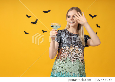 A girl at a party in the style of Halloween with a cocktail in her hands 107434932