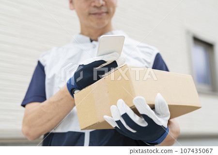 Delivery man in his 40s looking at his smartphone 107435067