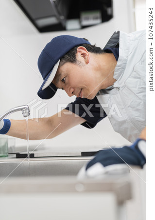 A male worker inspecting the faucet A male worker inspecting the faucet 107435243