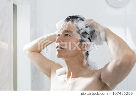 A man in his 40s washing his hair in the bath A man in his 40s washing his hair in the bath 107435296