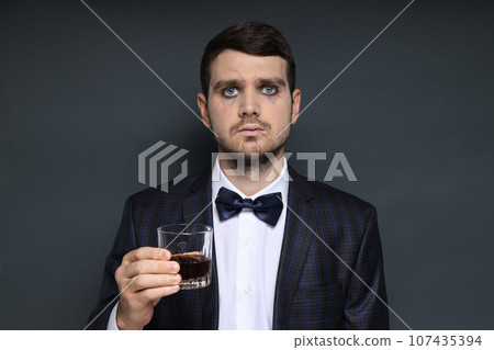 A man in a zombie costume with a drink in his hand on a black background A man in a zombie costume with a drink in his hand on a black background 107435394