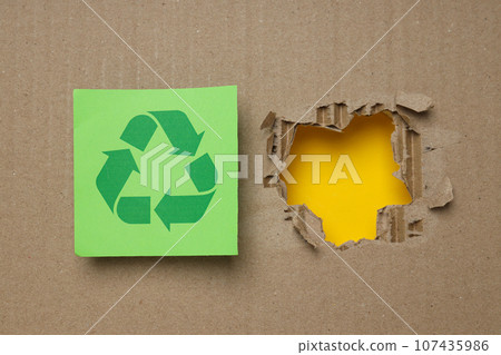 A hole in kraft cardboard on a yellow background. A hole in kraft cardboard on a yellow background. 107435986