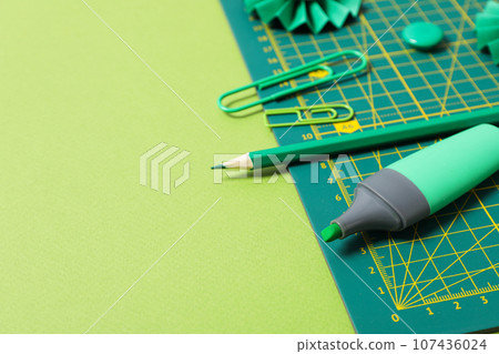 Concept of accessories for patchwork on a green background, mat cutting 107436024