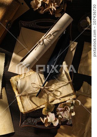 Vintage tray with old papers and feather on wooden background, top view 107436730