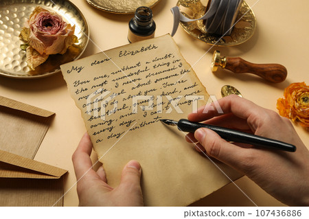 Letter with text and pen in hands, roses and vintage plates on beige background 107436886