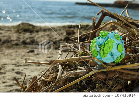 A paper model of the Earth is crumpled on the garbage A paper model of the Earth is crumpled on the garbage 107436914