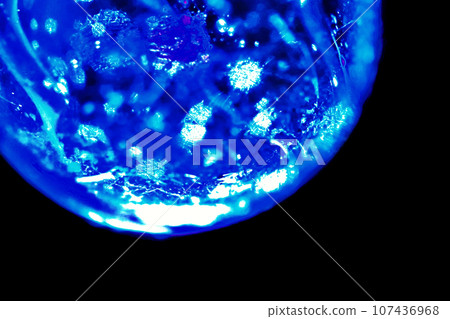 一幅宇宙想像圖像,其中一個像閃亮的藍色玻璃球一樣的球體在黑色背景上閃閃發光。 一幅宇宙想像圖像,其中一個像閃亮的藍色玻璃球一樣的球體在黑色背景上閃閃發光。 107436968