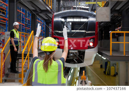 Young caucasian engineer woman or worker signal while engineer man checking electric train. Young caucasian engineer woman or worker signal while engineer man checking electric train. 107437166