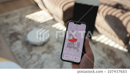 Woman presses the button on the app to turn on the modern robot vacuum cleaner. Modern technology of smart cleaning. Woman presses the button on the app to turn on the modern robot vacuum cleaner. Modern technology of smart cleaning. 107437683
