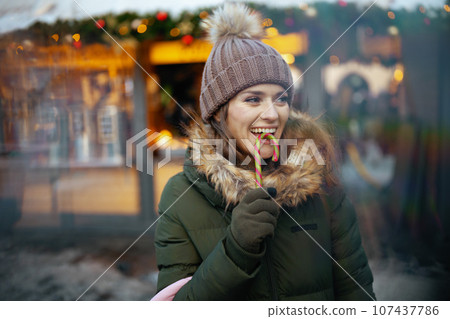 happy woman in green coat and brown hat at winter fair in city happy woman in green coat and brown hat at winter fair in city 107437786