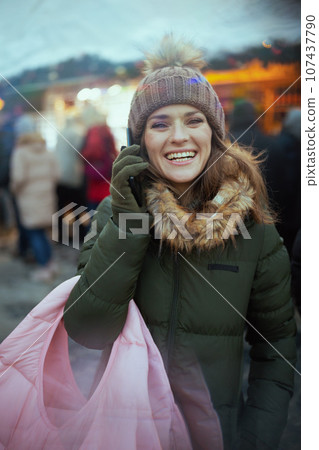 happy woman at christmas fair in city talking on phone 107437790