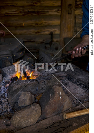 Blacksmith working metal with hammer on the anvil in the forge 107438554