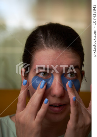 Woman is using cosmetic patches on face. 107438942