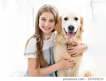 Portrait of pretty teenage girl hugging beautiful dog indoors 107439233