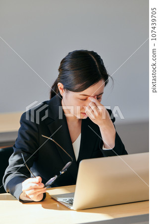 一位戴眼鏡、把手放在眉間的年輕女子 一位戴眼鏡、把手放在眉間的年輕女子 107439705