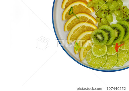 Fruit plate with grapes, kiwi, lime, pear and orange, sliced pieces on a white background, isolated 107440252