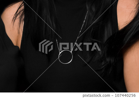 Close-up of girl in black dress and a pendant around the neck, fashion and style of clothing, close up 107440256