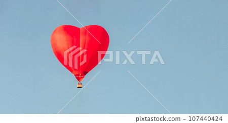 Hot air balloon in shape of heart in a blue sky. Space for text Hot air balloon in shape of heart in a blue sky. Space for text 107440424