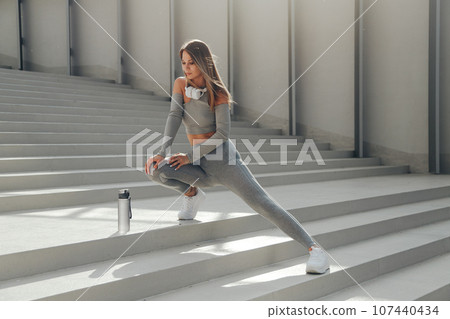 Sporty european woman stretching legs before workout outdoors 107440434
