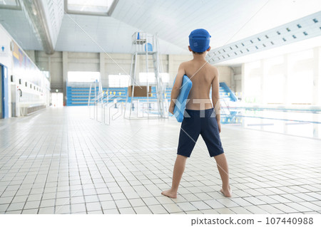 Rear view of a boy holding a beat board in an indoor pool Rear view of a boy holding a beat board in an indoor pool 107440988