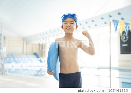 一個男孩在室內泳池裡拿著拍板打拳 一個男孩在室內泳池裡拿著拍板打拳 107441213