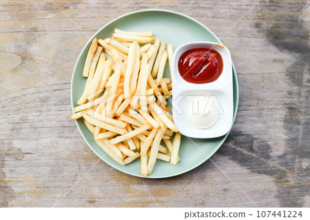 French fries or fried potato , fries with mayonnaise and tomato sauce 107441224