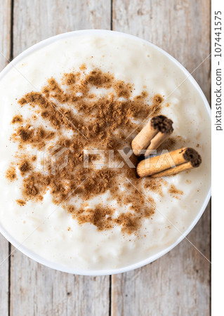 Arroz con leche. Rice pudding with cinnamon in bowl on wooden table. 107441575