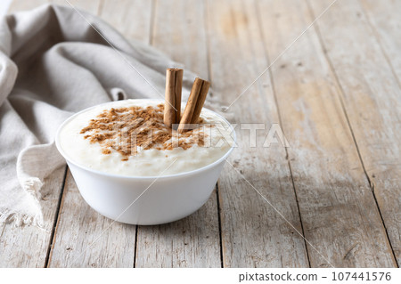 Arroz con leche. Rice pudding with cinnamon in bowl on wooden table. 107441576
