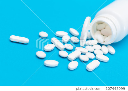 Pharmaceutical Industry and Medicinal Products - White Pills on Blue Table Pharmaceutical Industry and Medicinal Products - White Pills on Blue Table 107442099