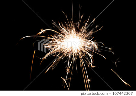 Sparkling burning sparkler on a black background. 107442307