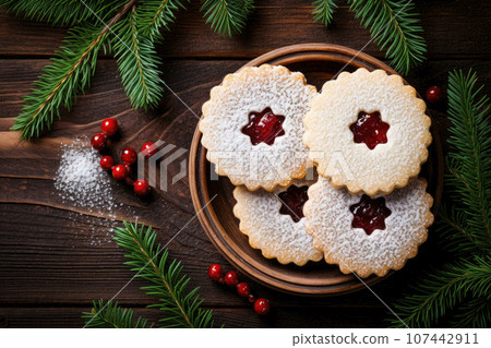 Linzer cookies with sweet jam and fir tree branches on wooden table. Top view Linzer cookies with sweet jam and fir tree branches on wooden table. Top view 107442911