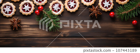 Linzer cookies with sweet jam and fir tree branches on wooden table. Top view Linzer cookies with sweet jam and fir tree branches on wooden table. Top view 107443189