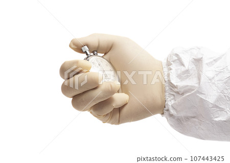 doctor's hand in white surgical medical gloves holds and white coverall suit an activated mechanical stopwatch doctor's hand in white surgical medical gloves holds and white coverall suit an activated mechanical stopwatch 107443425