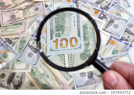 Magnifying glass on the background of bundle dollars - texture, background 107443752