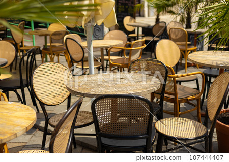 Empty restaurant summer terrace with tables and chairs. Reastaurant tables waiting for customers at an outdoor terrace, hipster style 107444407
