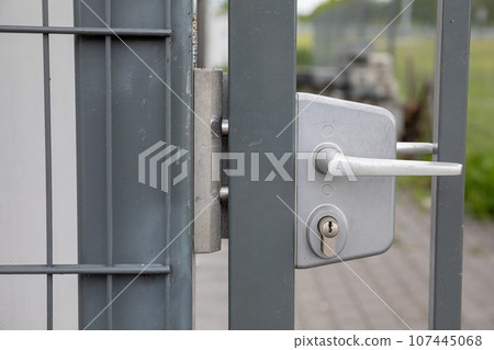 A close-up front view of the white handle on the steel fence gate. A close-up front view of the white handle on the steel fence gate. 107445068