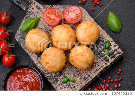 Delicious round balls of mozzarella and parmesan cheese with salt and breaded spices 107445320