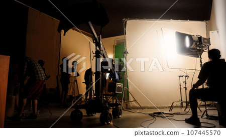 Silhouette images of making of or behind the scenes of video production which produced in the film studio that include all pro light and camera equipment and professional film crew with movie director Silhouette images of making of or behind the scenes of video production which produced in the film studio that include all pro light and camera equipment and professional film crew with movie director 107445570