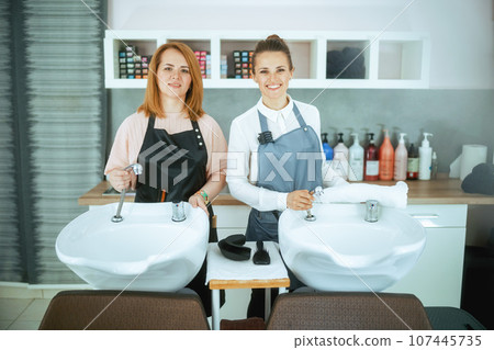 smiling two women hair salon workers in uniform in hair studio 107445735