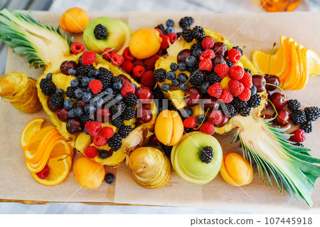 Beautiful and original serving of fruits and berries in pineapple.  107445918