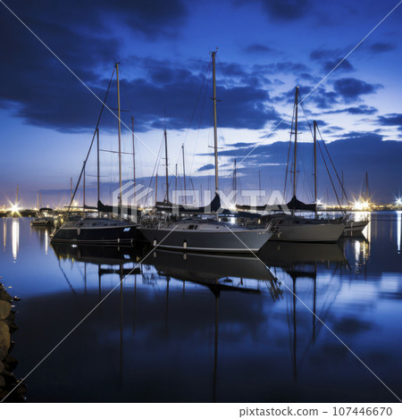 sailboats anchored in a harbor at night 107446670