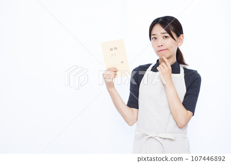 A housewife in her thirties who is worried about holding a salary bag in front of a white background 107446892