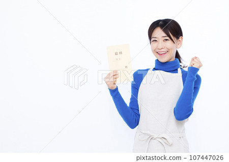 A housewife in her 30s holding a salary bag and doing a fist pump in front of a white background 107447026