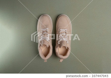 Classic hipster biege sneakers on green background, active lifestyle. Summer concept. top view 107447043