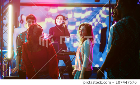 Friends doing dance battle at party, showing different funky moves for breakdance on the dance floor. Group of people showing off dancing skills on electronic music, clubbing at night. Friends doing dance battle at party, showing different funky moves for breakdance on the dance floor. Group of people showing off dancing skills on electronic music, clubbing at night. 107447576
